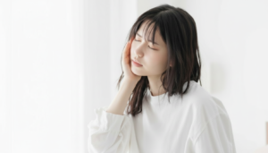 顎の違和感で頬に手を充てる女性